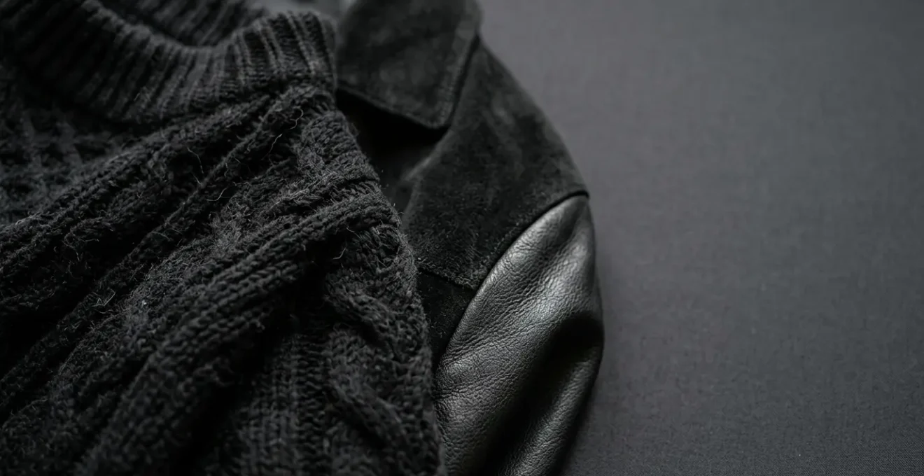 Close-up editorial photograph showing the tactile contrast between soft black knitwear and structured black leather surfaces in a high-end fashion context