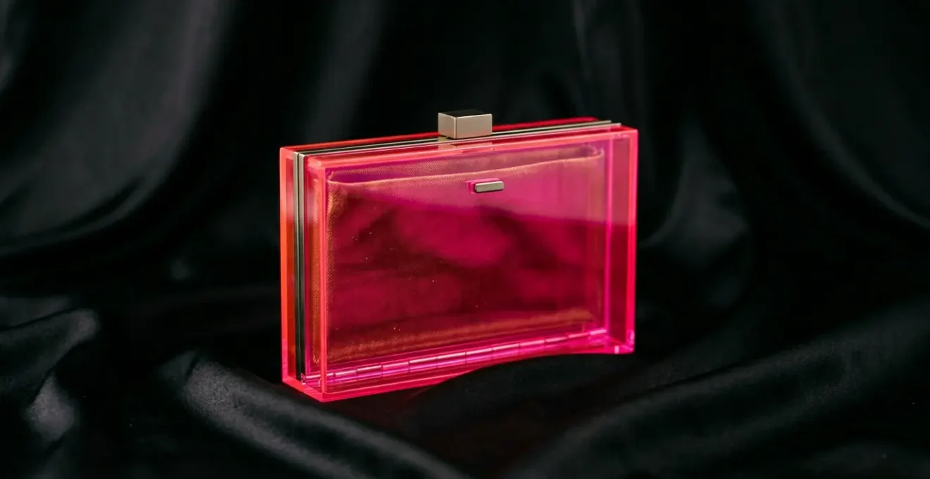 Elegant neon pink clutch held beside a classic little black dress in sophisticated evening setting