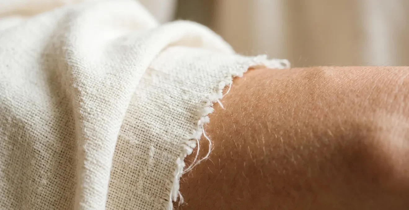 Close-up of organic cotton fabric against healthy skin showing natural fiber texture and gentle contact