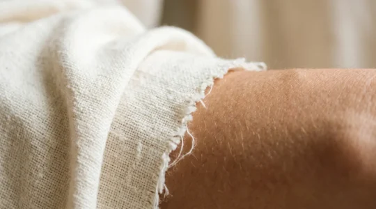 Close-up of organic cotton fabric against healthy skin showing natural fiber texture and gentle contact